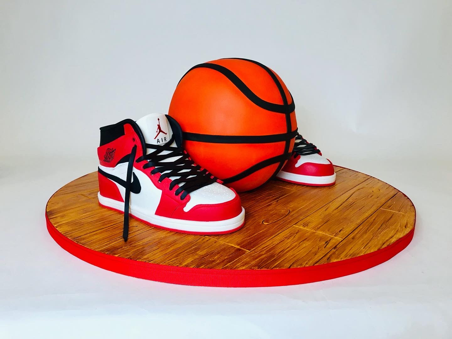 Basketball and red sneakers on a wooden platform with a white background