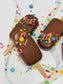 Chocolate-dipped cakesicles with colorful sprinkles on a polka dot background