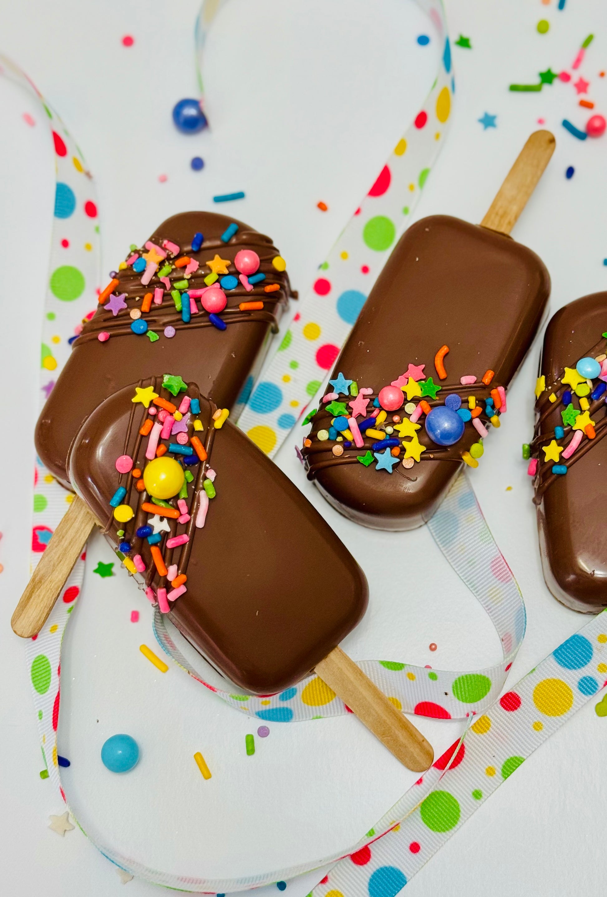 Chocolate-dipped treats with colorful sprinkles on a white background with polka dots