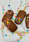 Chocolate-dipped treats with colorful sprinkles on a white background with polka dots