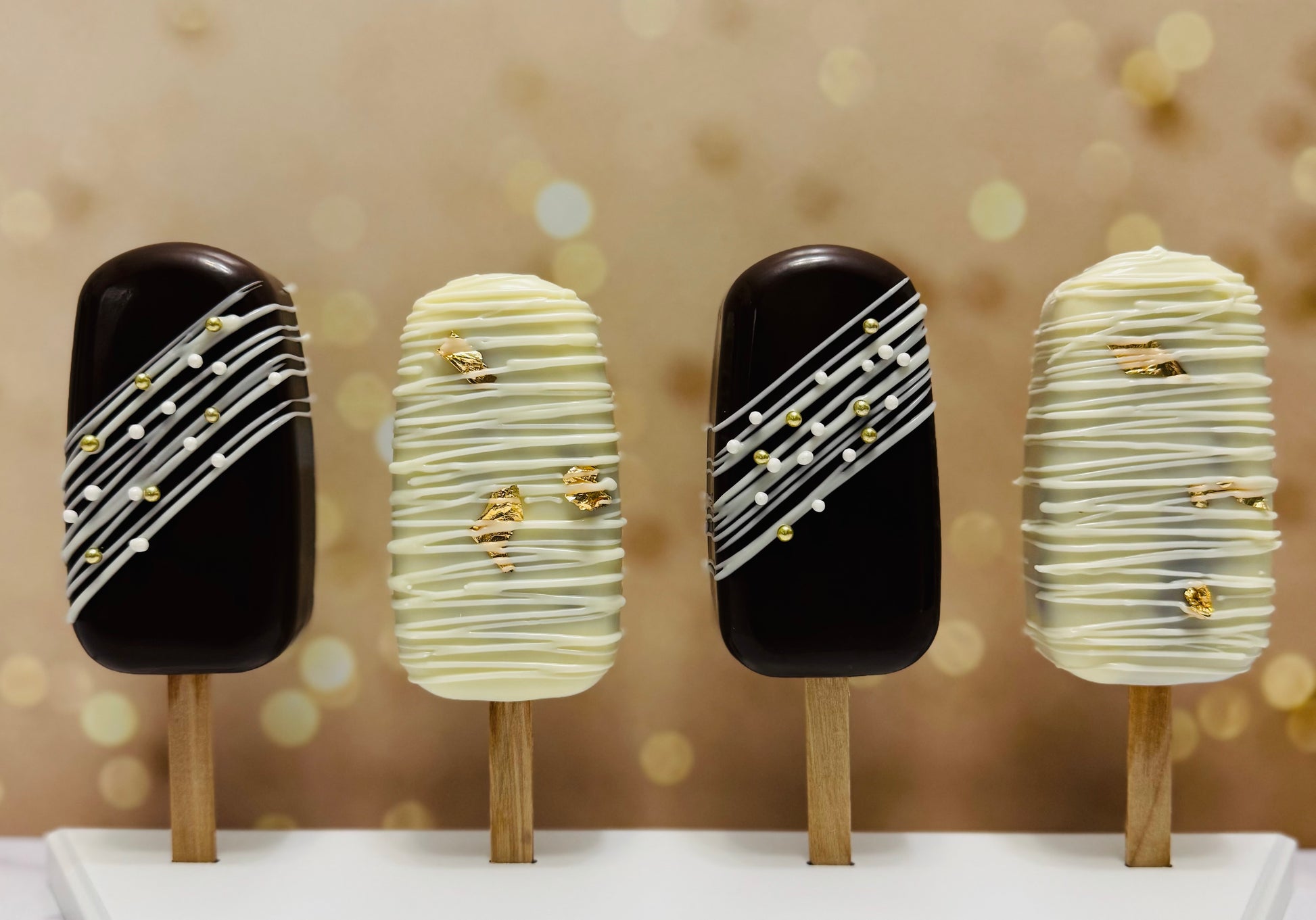 Four ice cream cakesicles with decorative patterns on a blurred background