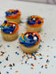 Cupcakes with blue and orange frosting on a white surface with sprinkles.