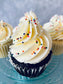 Cupcakes with white frosting and colorful sprinkles on a blue plate.