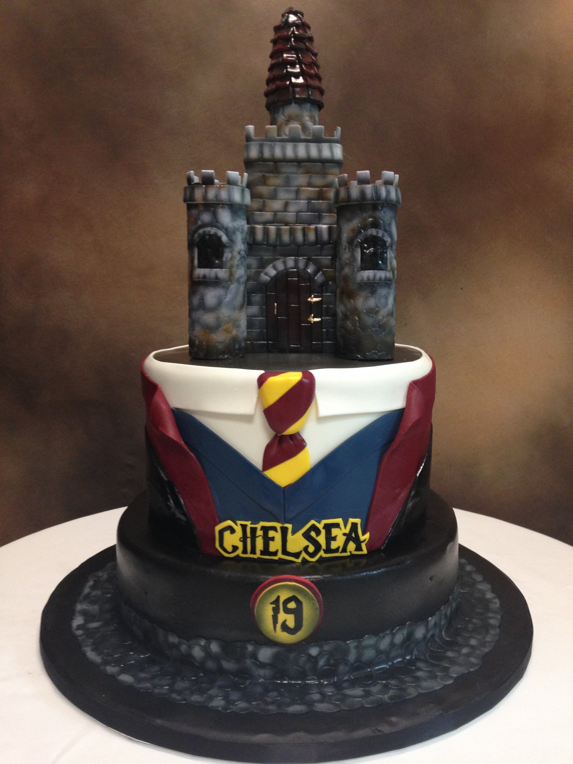 Cake with a castle topper and Chelsea FC logo on a brown background