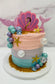 Decorative cake with mermaid-themed decorations on a white marble surface