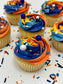 Cupcakes with blue and orange frosting on a white surface with sprinkles.