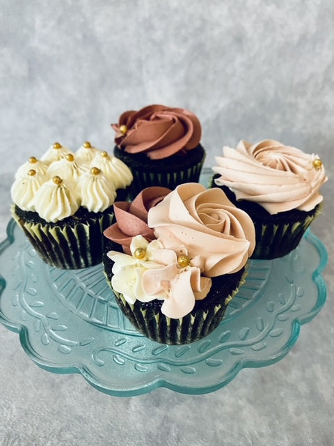 Decorative cupcakes with swirl frosting on a glass plate against a gray background