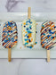 Three decorated ice cream popsicles on a white surface with a marble background