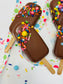 Chocolate-dipped popsicles with colorful sprinkles on a polka dot background