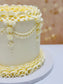White cake with yellow ruffles on a white surface with a blurred gold background