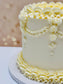 White cake with decorative yellow icing on a blurred background